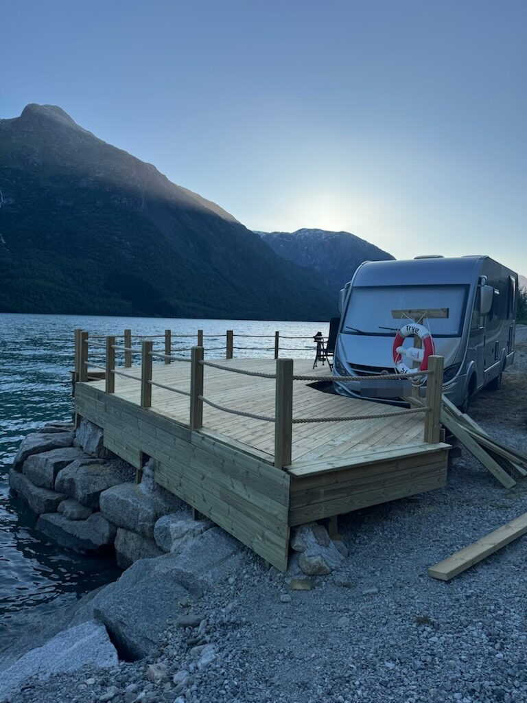 Bubil parkert inntil treterrassen ved vatnet i kveldslys