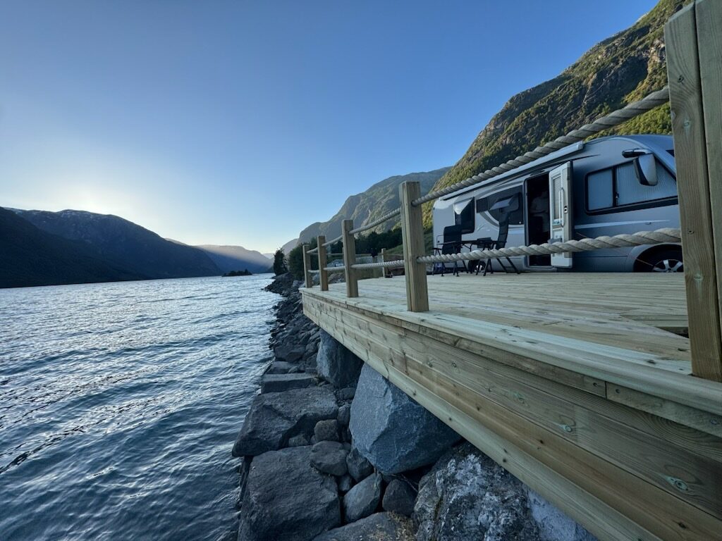 Treterrasse med taurekkverk langs vasskanten og bubil ved sida