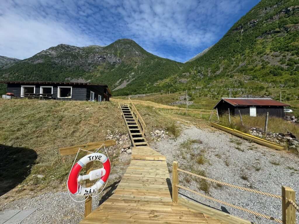Trapp frå bygningen ned til treterrassen, med livbøye og fjell bak